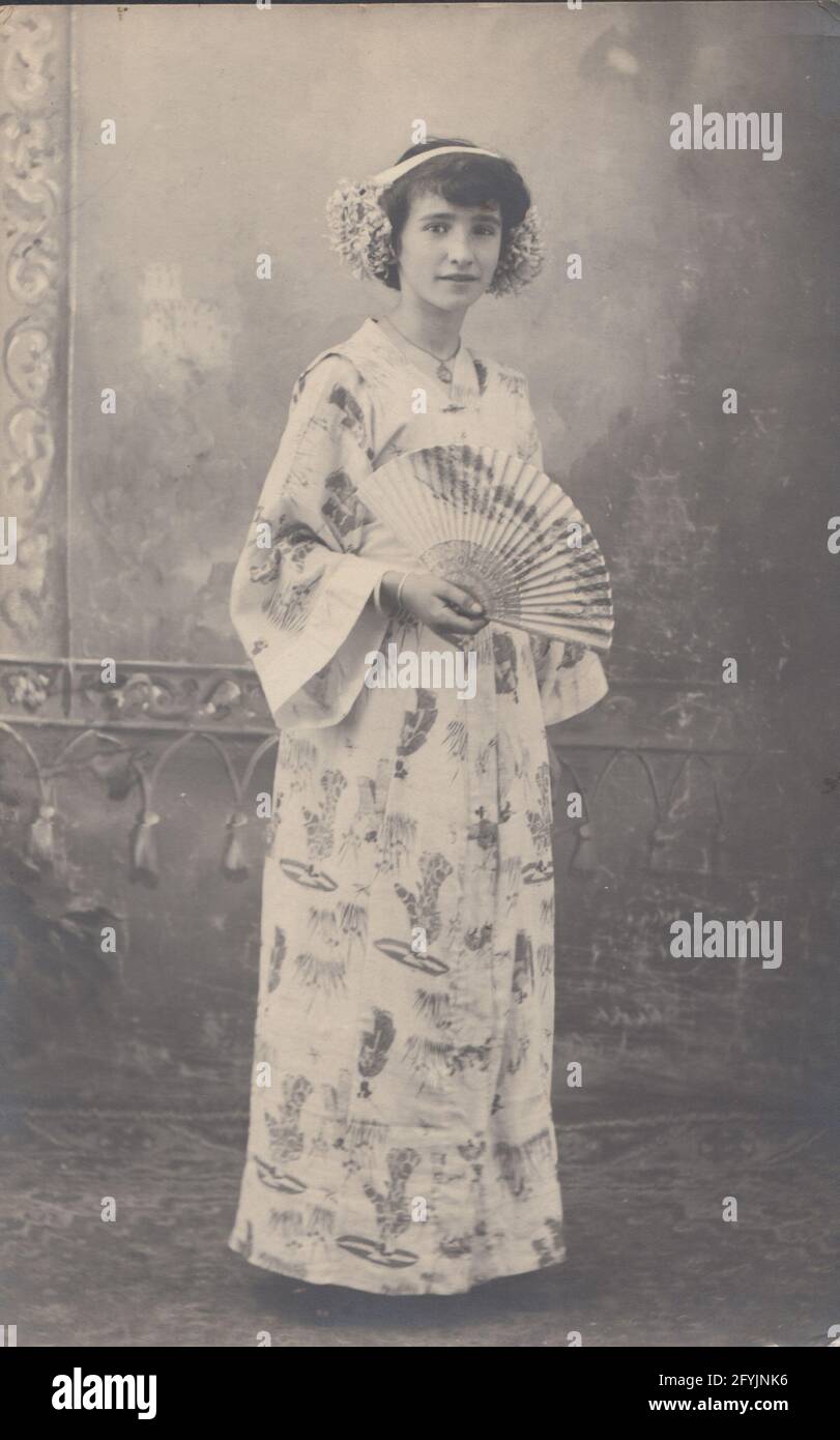 Cartolina fotografica d'epoca che mostra una ragazza vestita con un kimono giapponese e con in mano un fan. Foto Stock