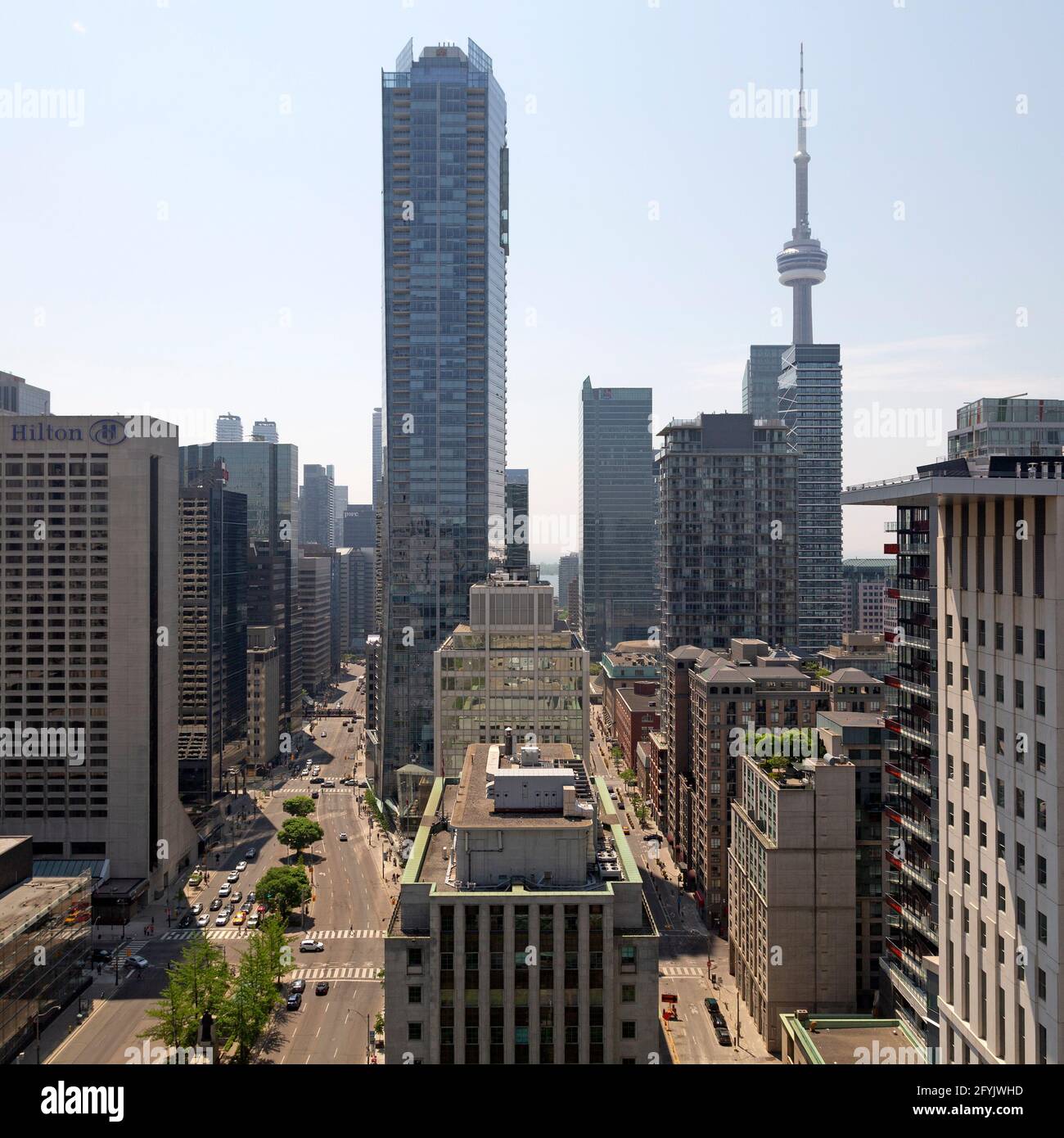 Edifici a più piani su Univeristy Avenue nel centro di Toronto in Ontario, Canada. La CN Tower è vista innalzarsi sopra i grattacieli in primo piano. Foto Stock