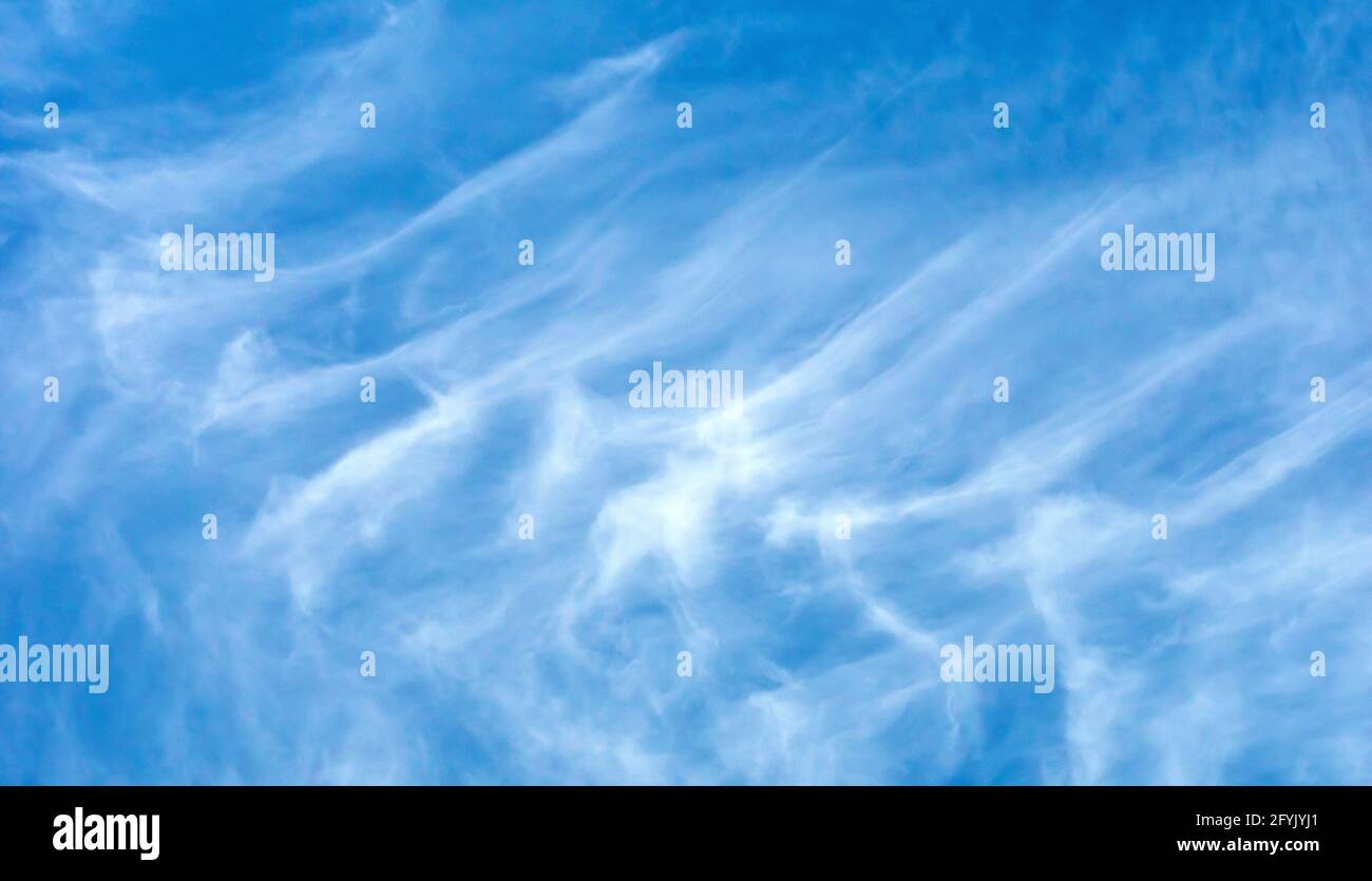 Nuvole di cirrus bianco ad alto livello distorte e distese da venti di alto livello sparati contro un cielo blu. Foto Stock