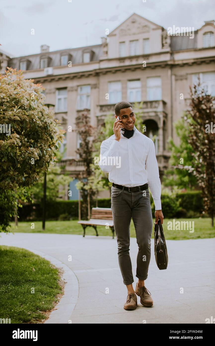 Bel giovane uomo d'affari afro-americano che usa un cellulare su una strada Foto Stock