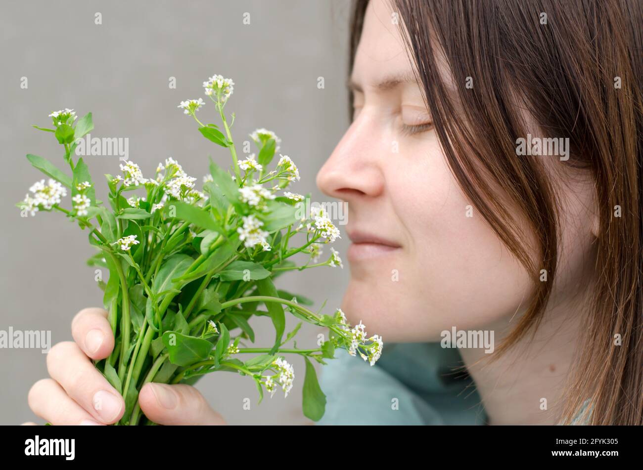 Bella giovane donna sniffing fiori selvatici. Un bouquet di fiori in mani femminili. Atmosfera primaverile e primaverile Foto Stock