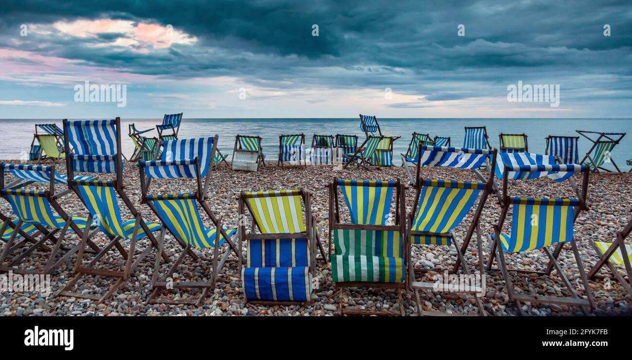 Sedie a sdraio sulla spiaggia di ciottoli a Beer in Devon in una serata estiva. Foto Stock