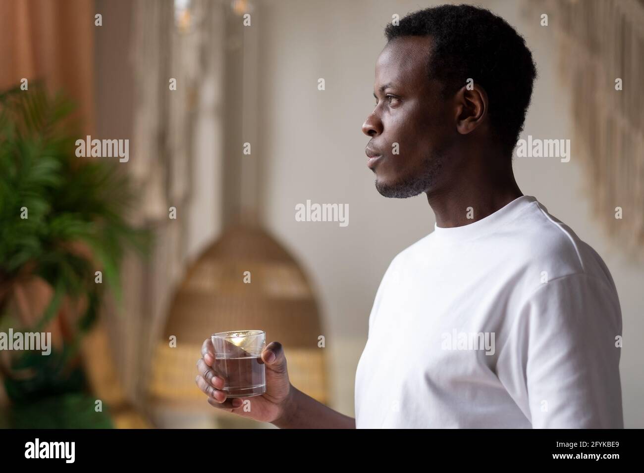 Atleta africano a casa con un bicchiere d'acqua dopo l'allenamento sportivo. Foto Stock