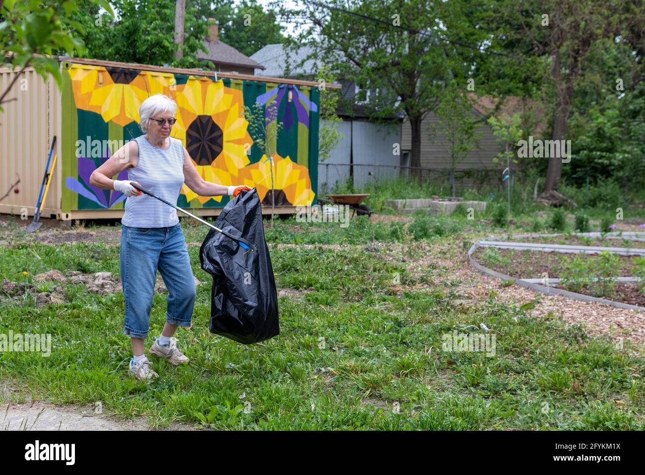 Detroit, Micigan -Susan Newell, 72 anni, raccoglie la lettiera in un giardino durante una pulizia annuale in tutta la città chiamata Motor City Makeover. Foto Stock
