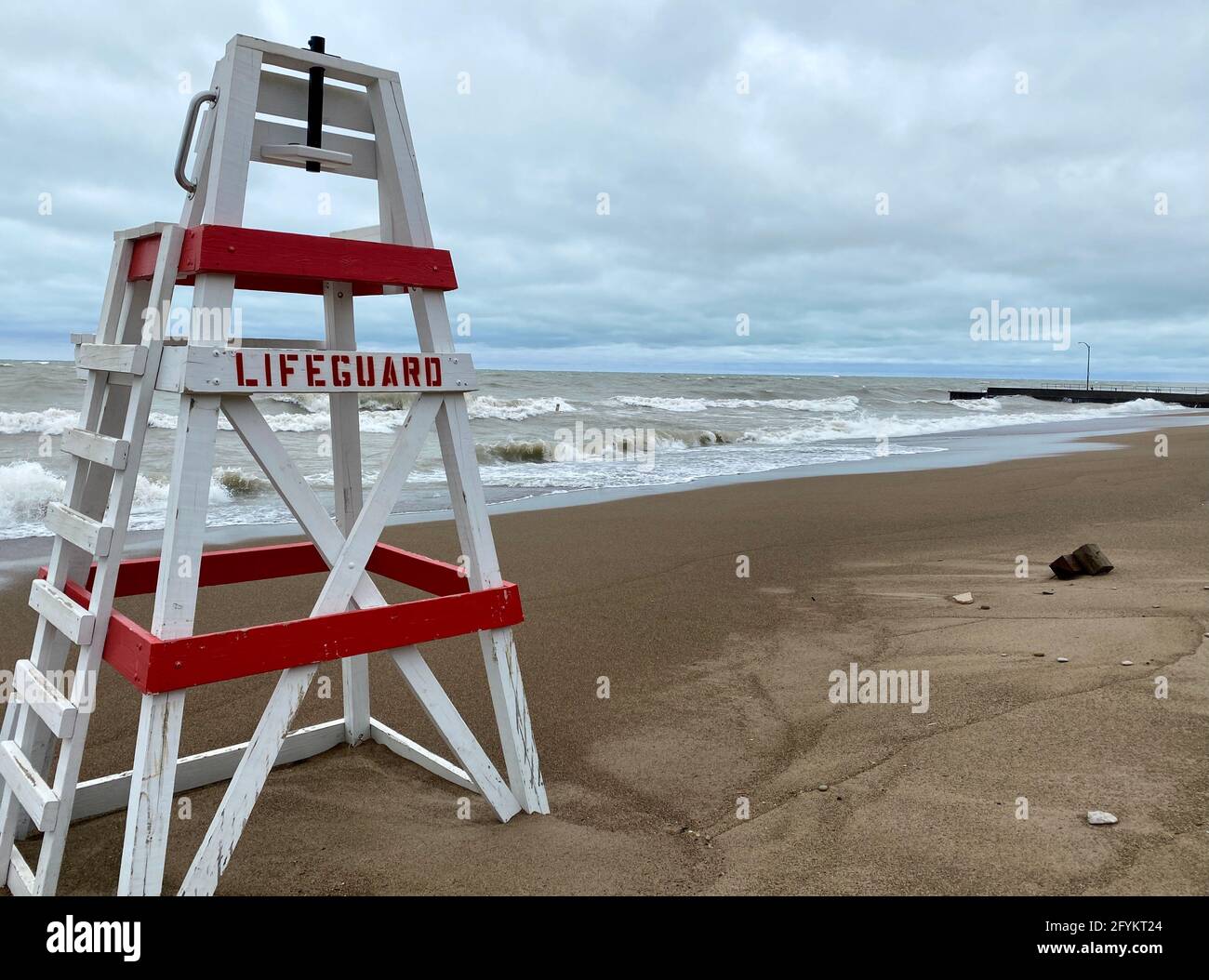 Sedia salvagente vuota su Tower Beach lungo la costa dell'Illinois del lago Michigan in una giornata intensa, mentre le onde si infrangono lungo la riva sullo sfondo. Foto Stock