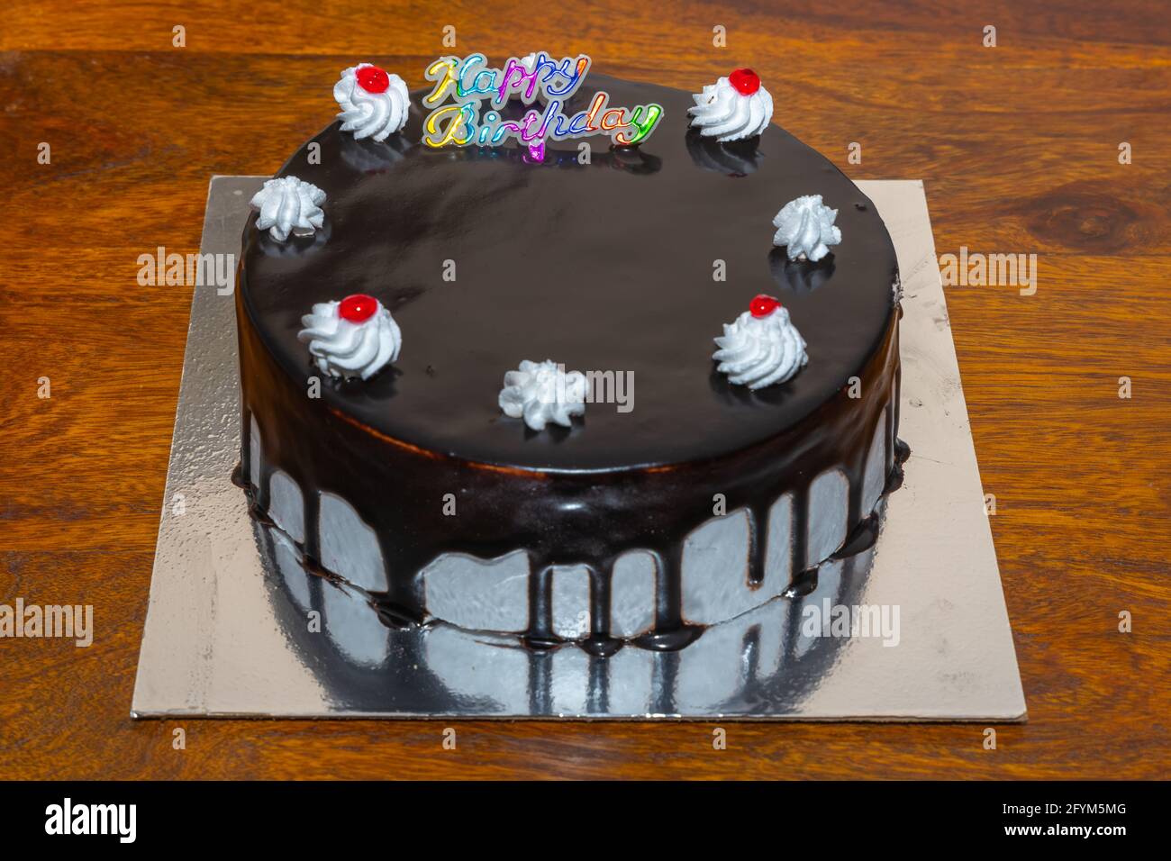 Una torta al cioccolato fondente con ciliegia e buon compleanno scritto su di essa Foto Stock