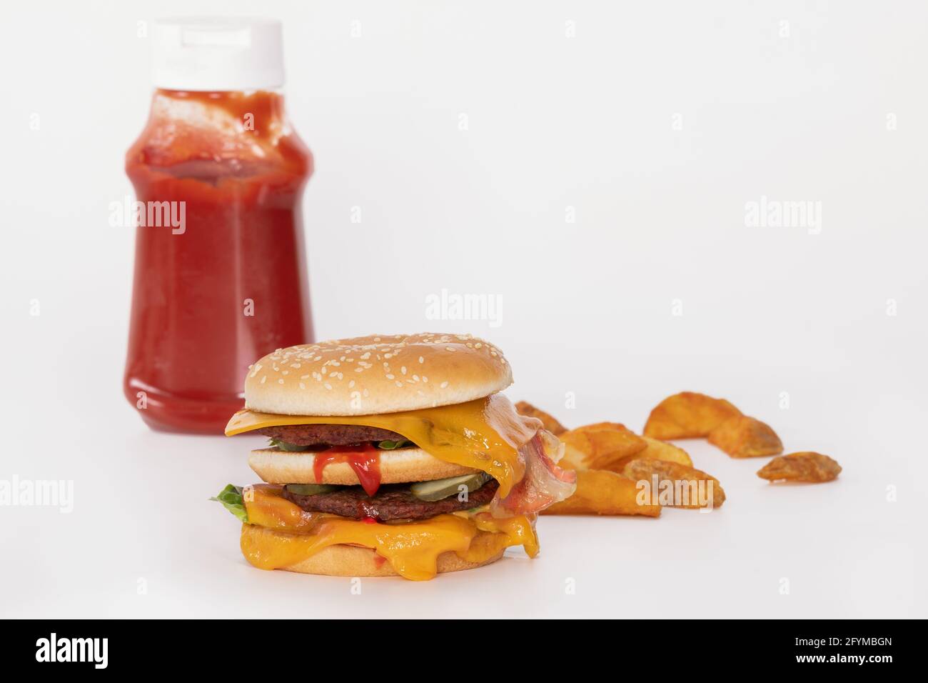 Hamburger doppio con pancetta, fette di patate e bottiglia di ketchup Foto Stock