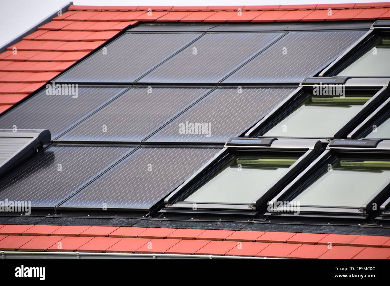 moduli solari per la produzione di elettricità dalla luce solare integrati nel tetto di una casa indipendente di fronte al cielo Foto Stock