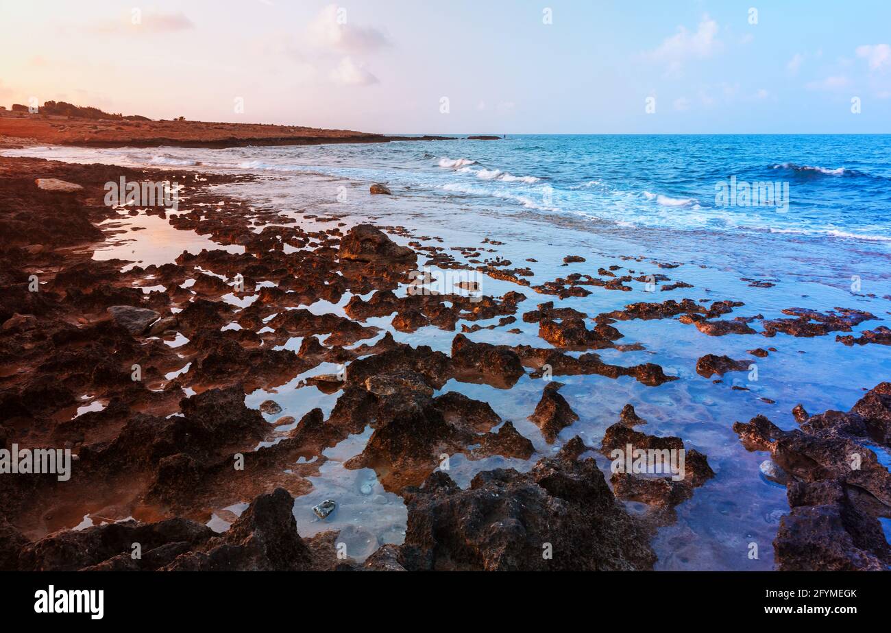 Costa rocciosa rossa del Mar Mediterraneo all'alba. Paesaggio estivo di Ayia Napa, isola di Cipro Foto Stock