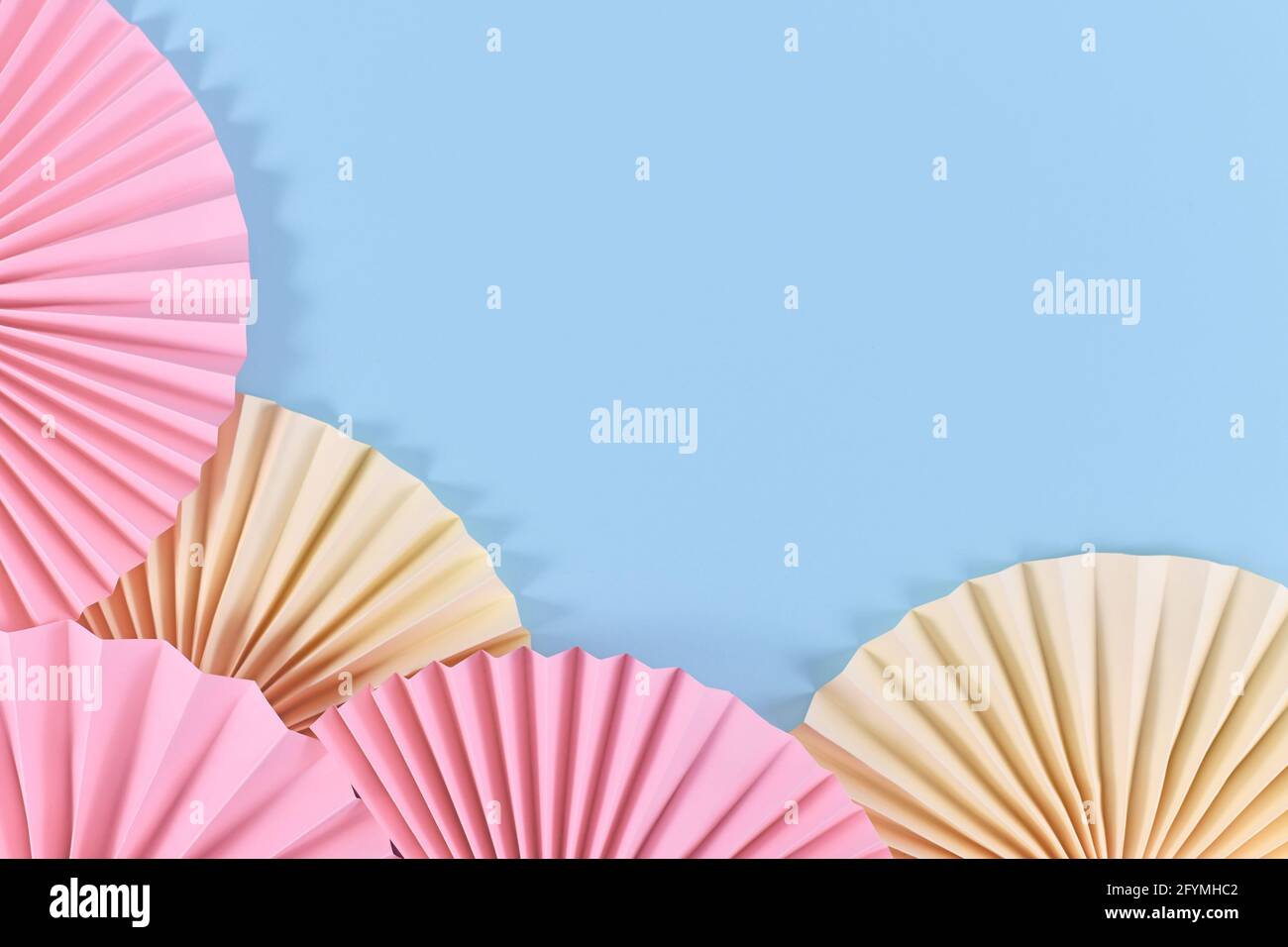 Rosette di carta artigianali rosa e beige su sfondo blu con spazio di copia vuoto al centro Foto Stock