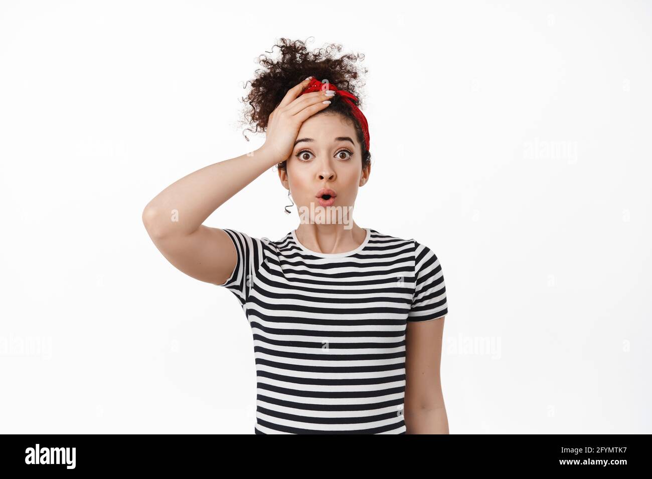 Scioccato bruna donna gaspa, tenendo la mano sulla testa e stare stallito alla macchina fotografica, guardando turbato e preoccupato, dimenticato ricordare qualcosa di importante Foto Stock