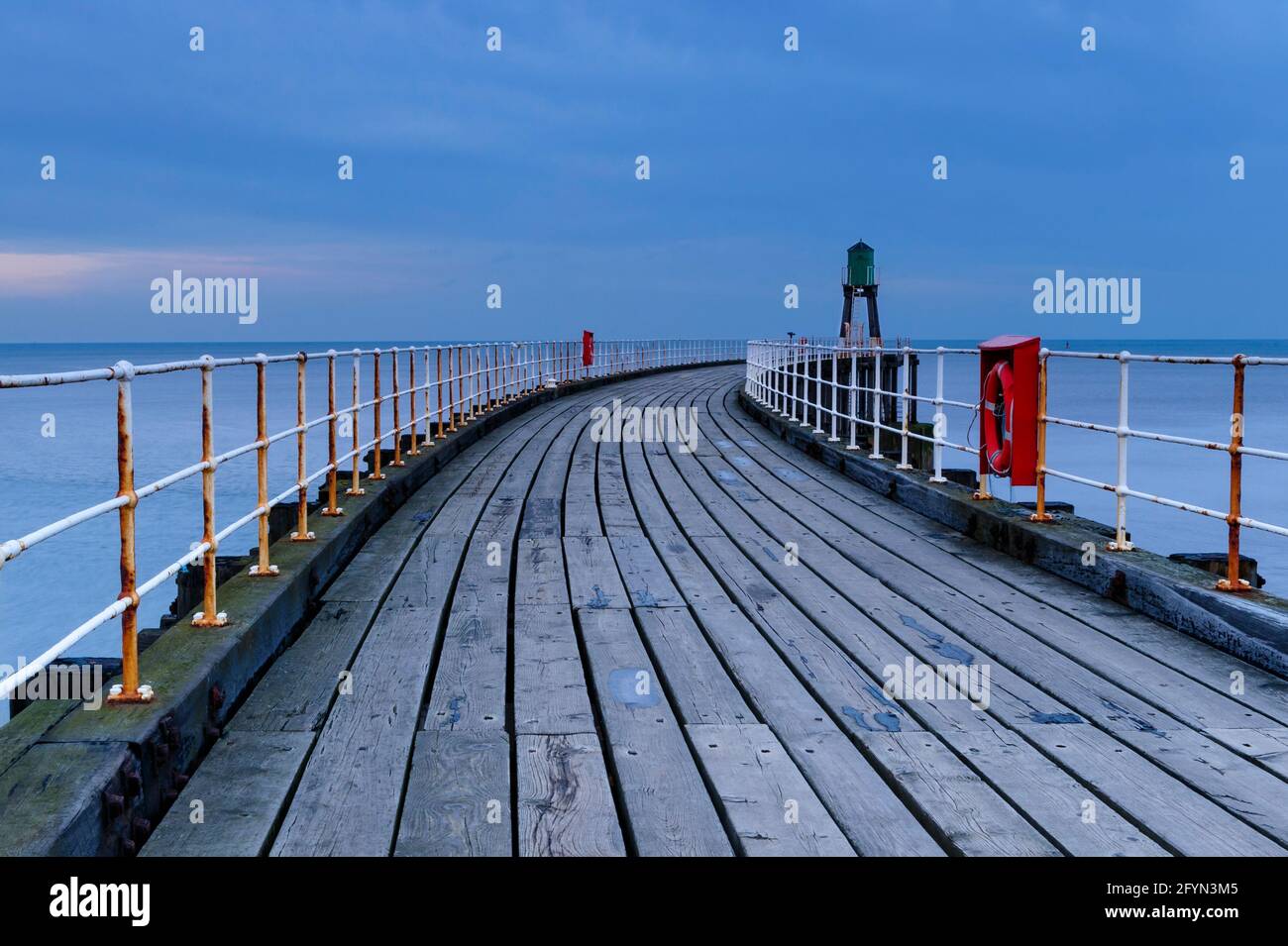 Whitby's West Pier (mare calmo, passerella in legno, faro, spettacolare luce notturna blu dell'ora) - ingresso al porto di Whitby, costa del Nord Yorkshire, Inghilterra Regno Unito Foto Stock