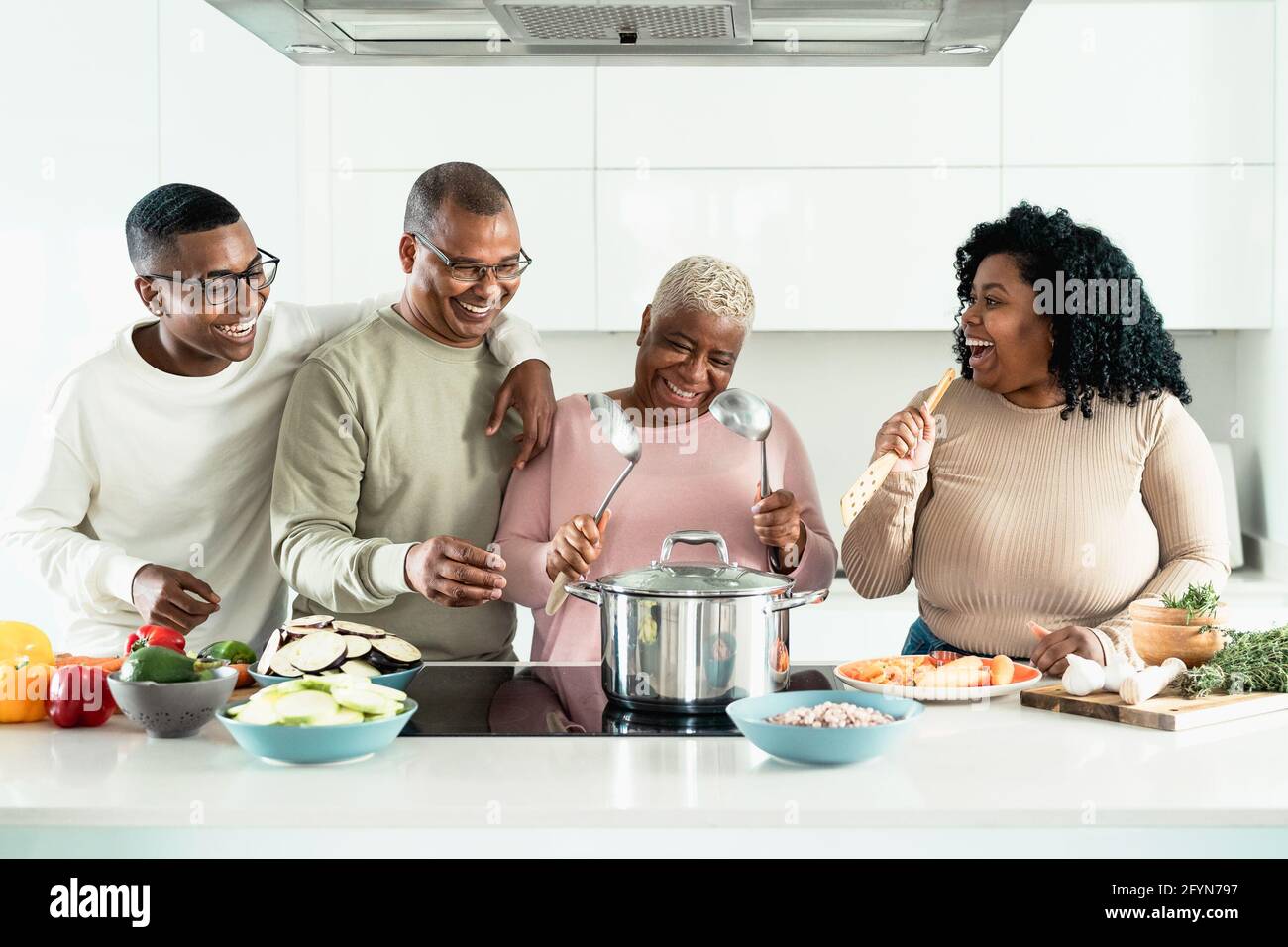 Felice famiglia nera avendo divertimento cucinare insieme in cucina moderna - concetto di unità di cibo e genitori Foto Stock