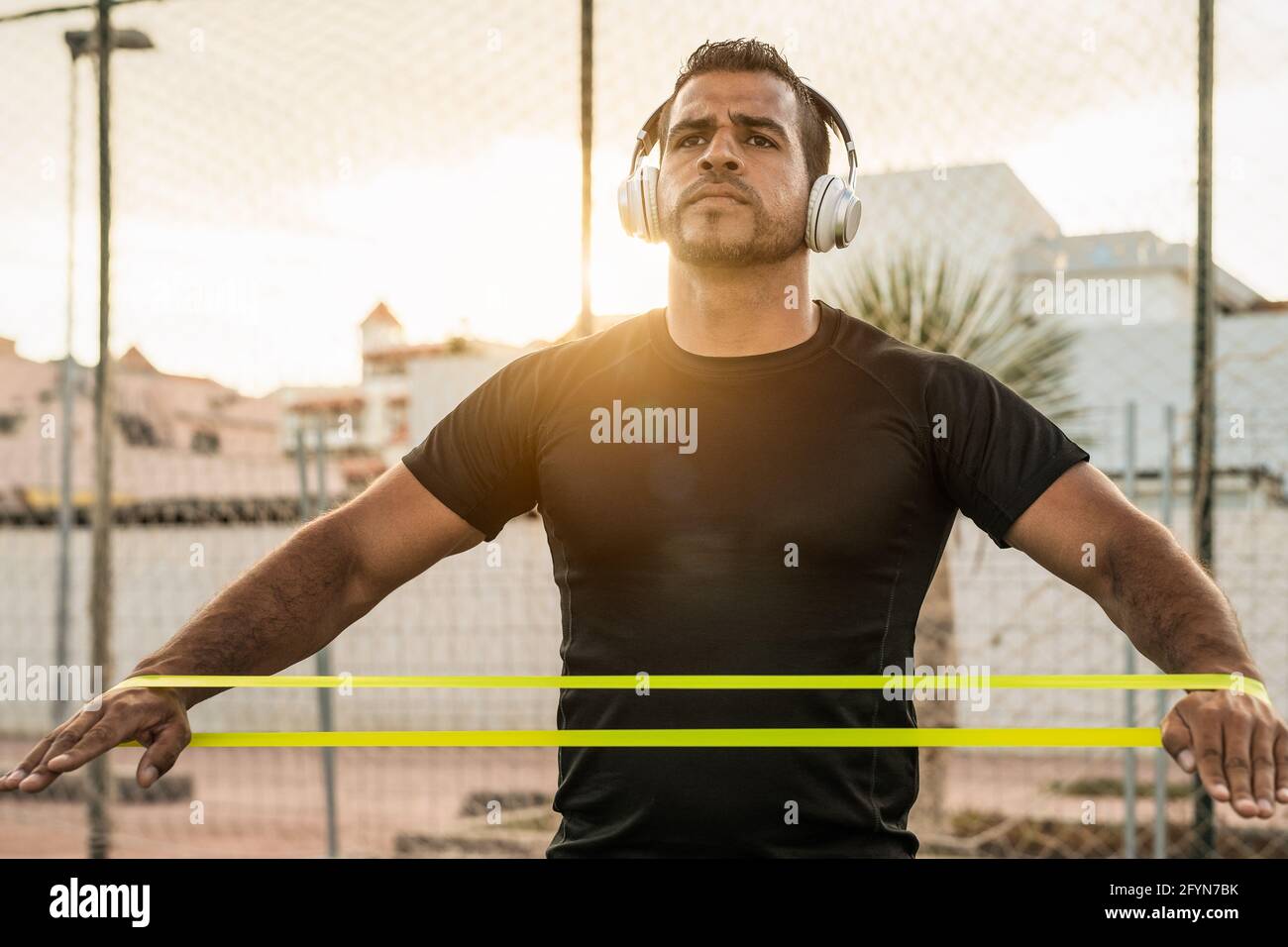 Sessione di esercizi di allenamento dell'uomo latino all'ora del tramonto - Giovane uomo ispanico allenarsi sodo mentre si ascolta la musica con le cuffie Foto Stock