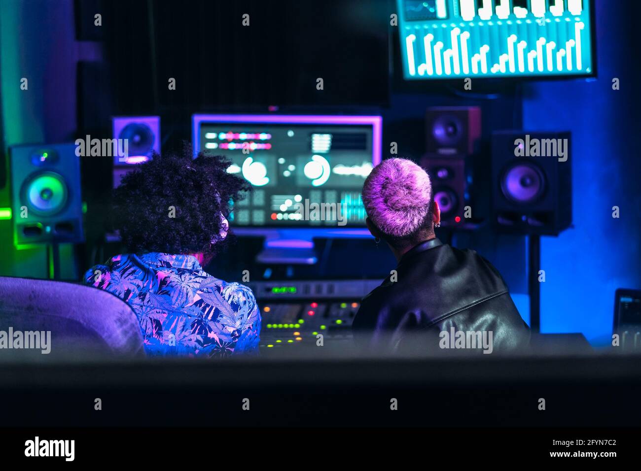 Giovani tecnici audio si divertono a lavorare con il suono del mixer pannello di controllo nello studio di registrazione musicale Foto Stock