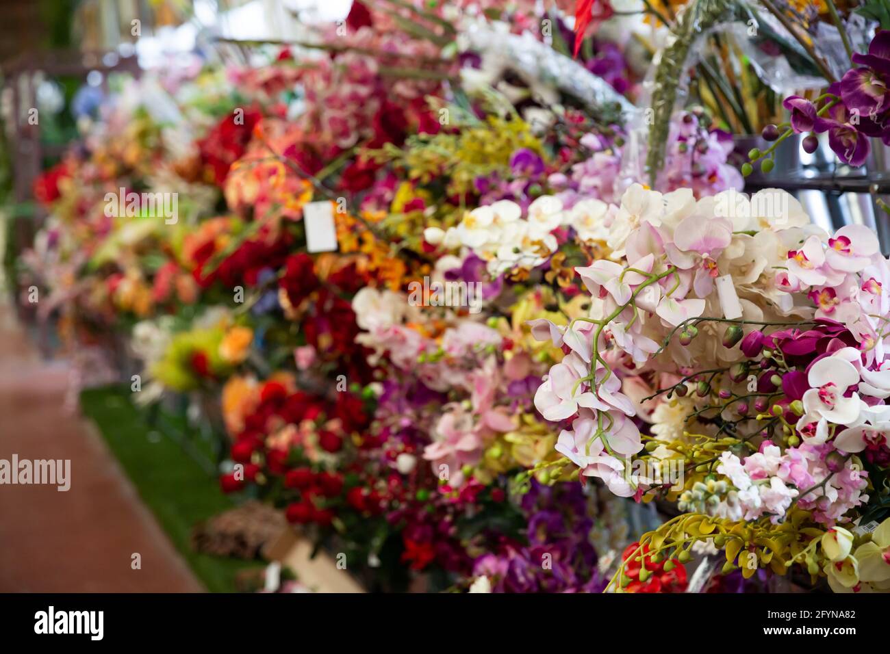 Vetrina colorata di fioreria con ampio assortimento di fiori artificiali Foto Stock