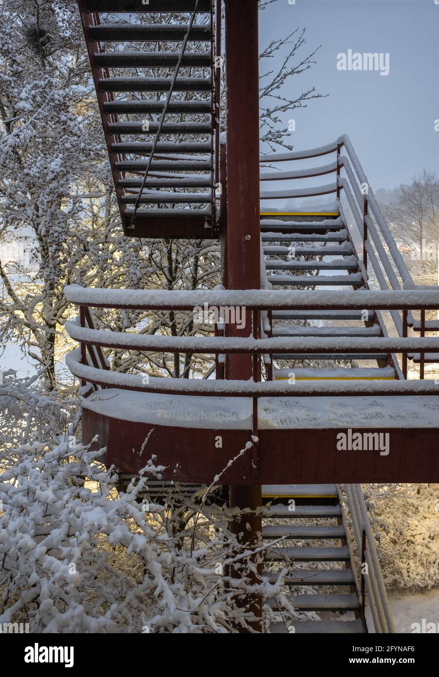 Scale esterne in metallo rosso di un edificio industriale a Zurigo in una serata invernale innevata con luci. Foto Stock