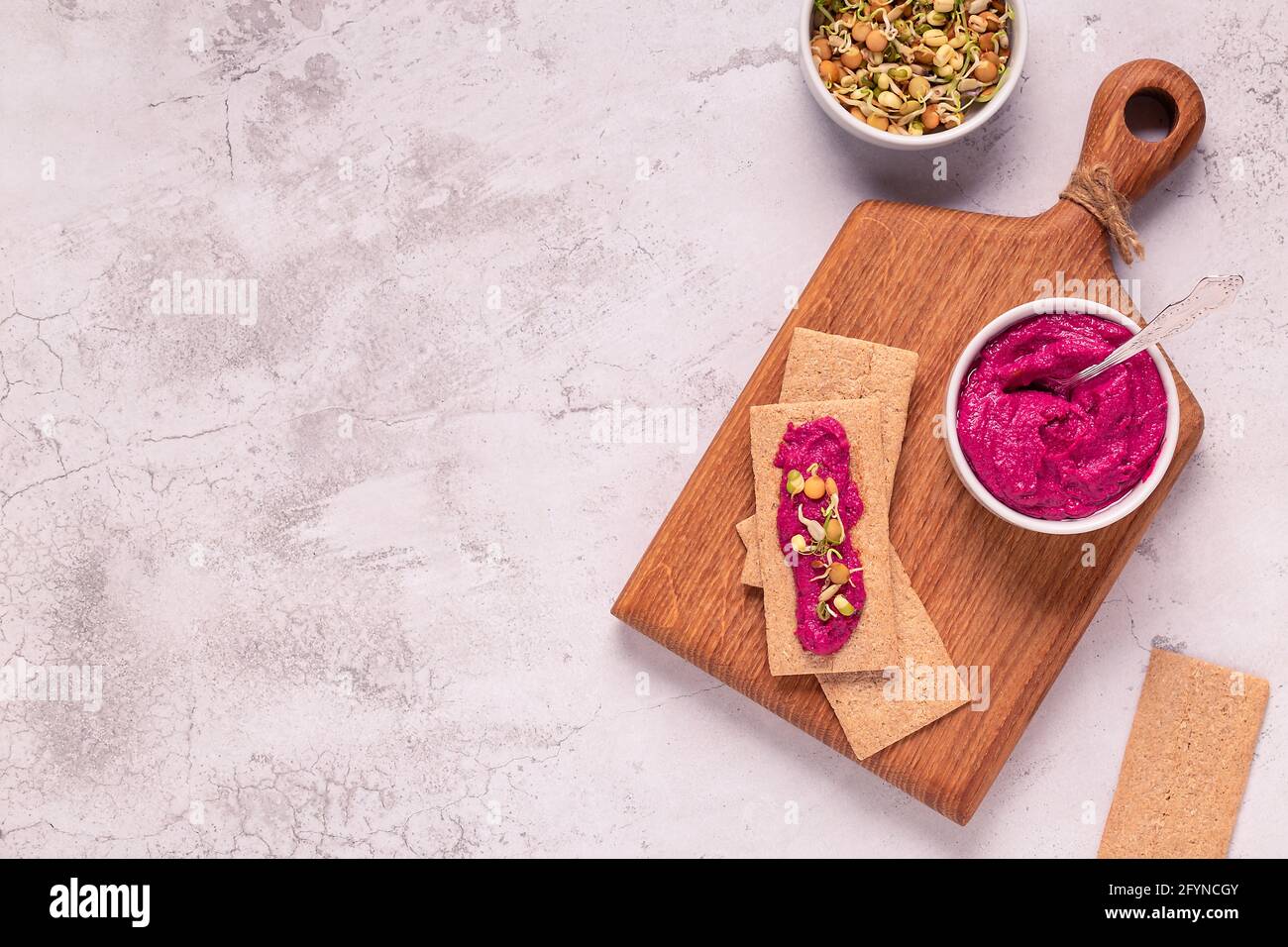 Spuntino vegetariano, vegano - hummus di barbabietola, grani germogliati e patatine di grano intero. Foto Stock