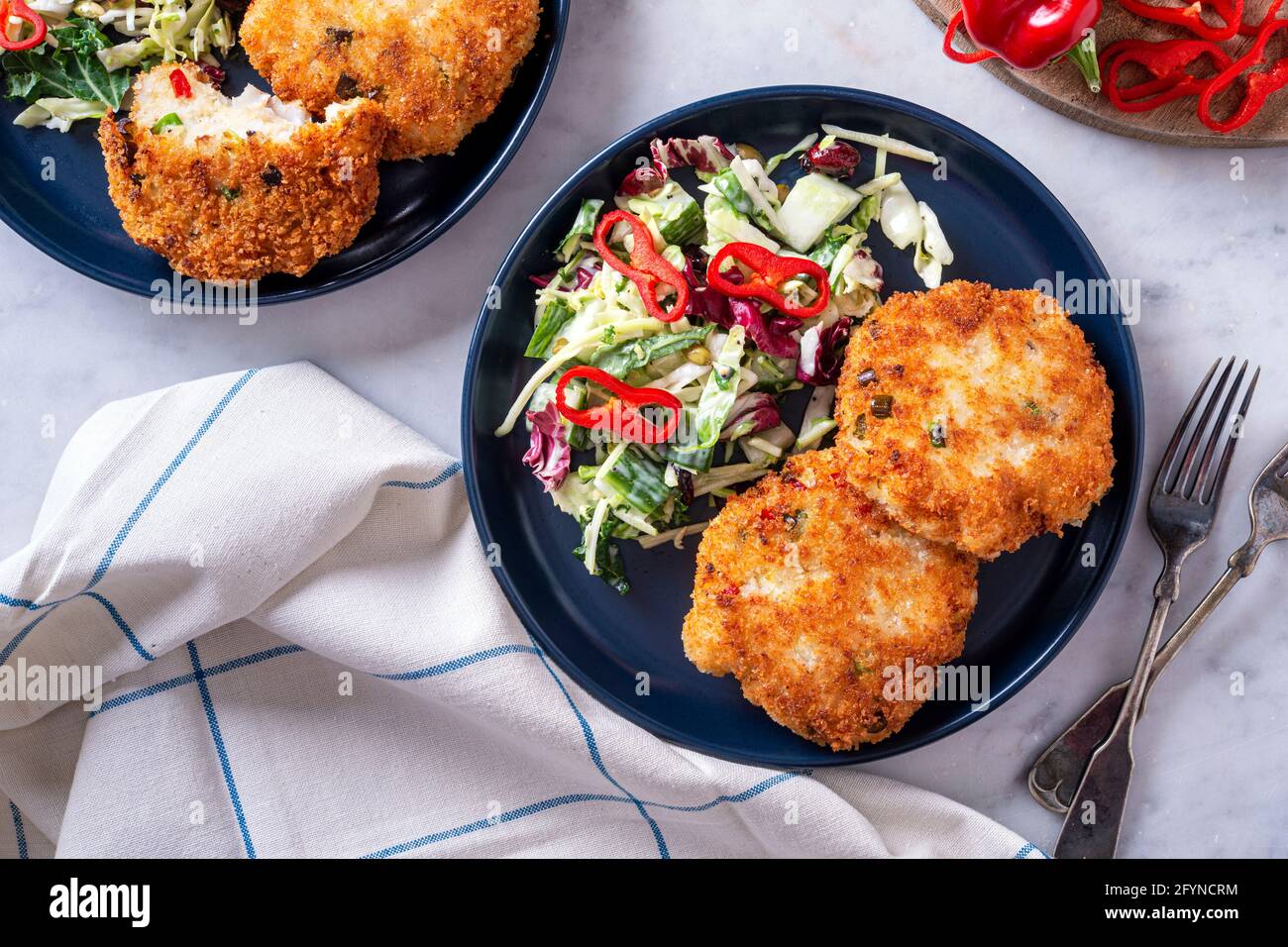 Deliziose torte di pesce in crosta di panko con insalata di cavolo e pepe rosso. Foto Stock