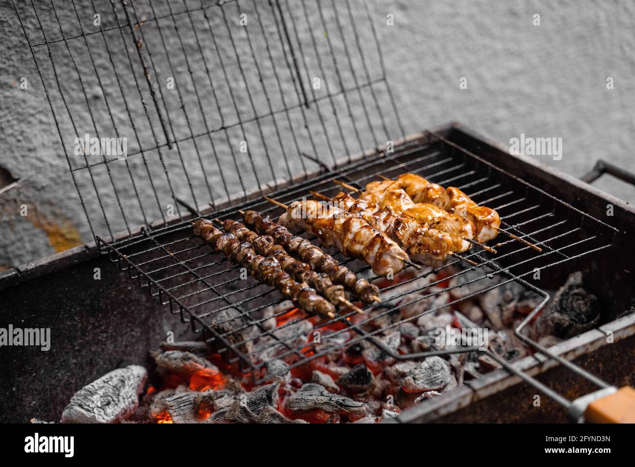 Carne grigliata su spiedini di legno su griglia di metallo su carbone.  Cottura di pollo, cuori Foto stock - Alamy