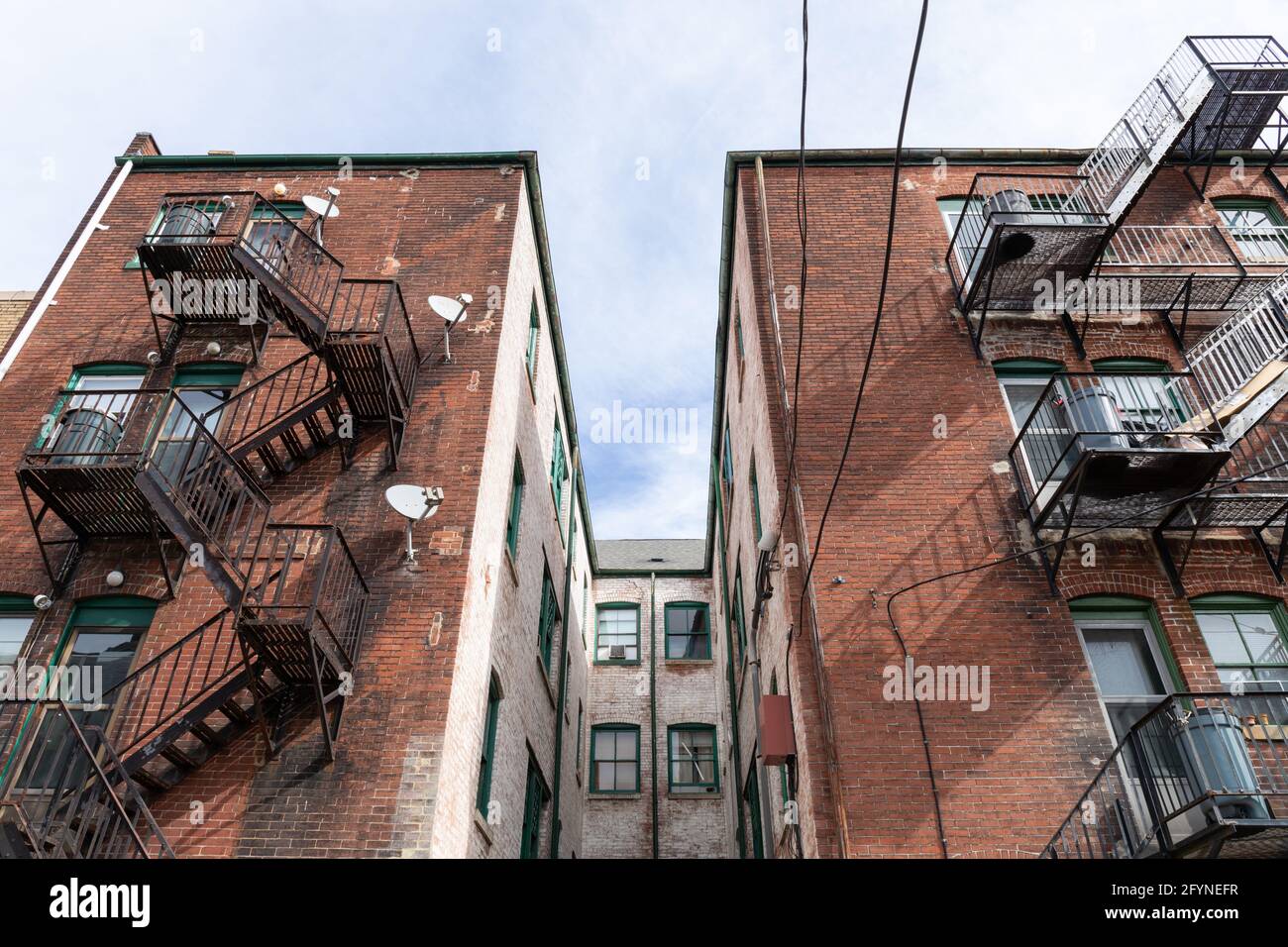 Vista centrata di un pozzo di luce tra le ali dell'edificio, scappate di fuoco metallico, composizione dell'alloggio urbano, aspetto orizzontale Foto Stock