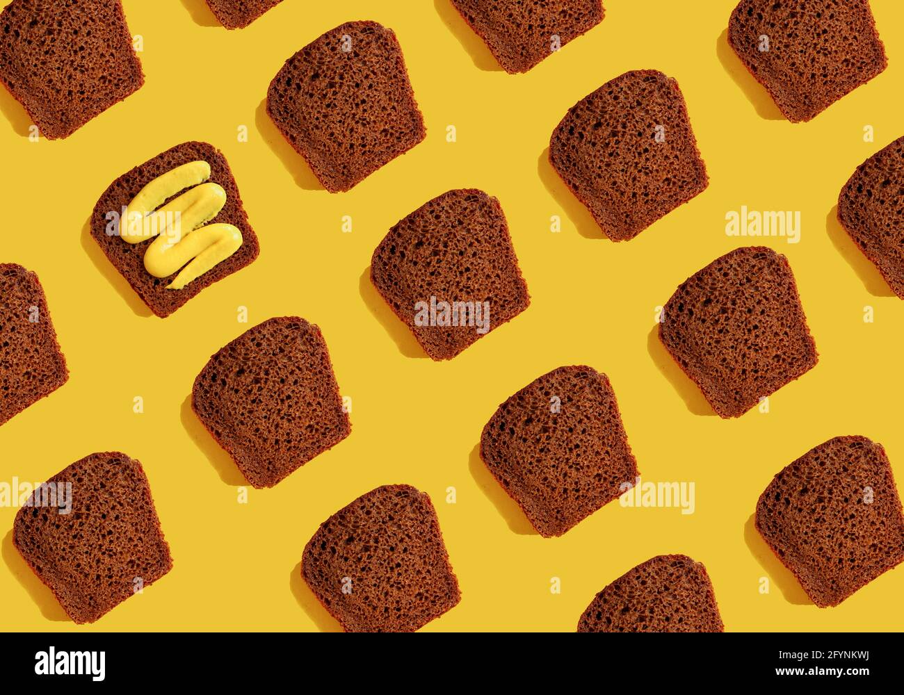 Pezzi di pane di segale scuro su sfondo giallo. Modello di cibo. Foto Stock