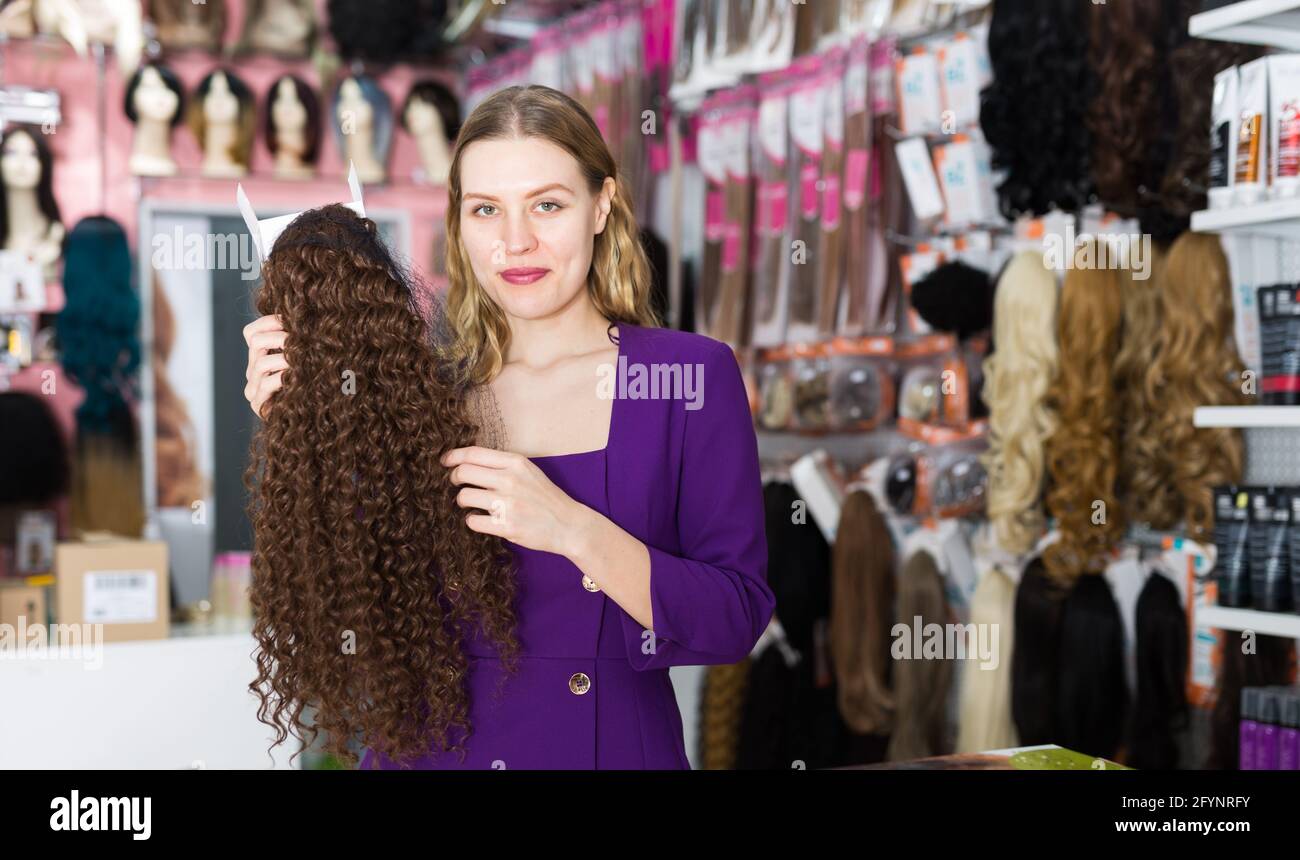 Giovane donna di stile che sceglie la parrucca dei capelli naturali in boutique  di specialità Foto stock - Alamy