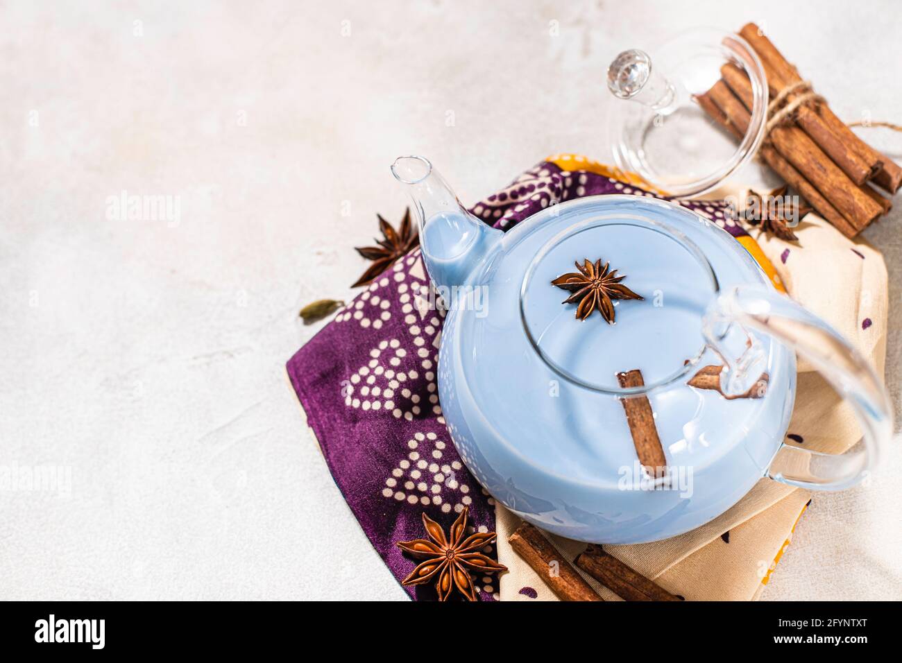 Tè blu masala tè in una teiera di vetro. Tè indiano masala aromatizzato con latte e spezie. Primo piano, spazio di copia. Foto Stock