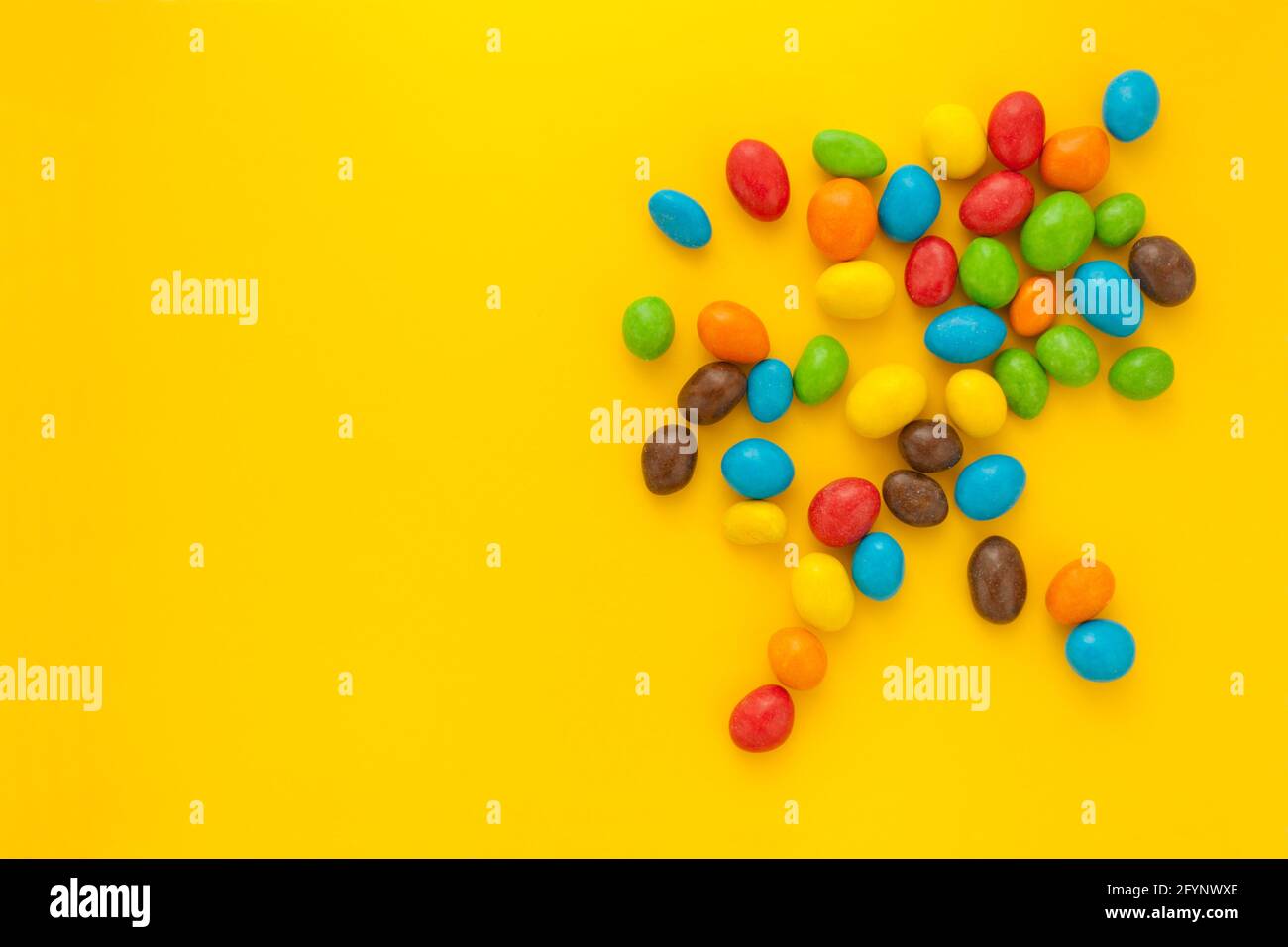caramelle colorate o noci sdoppiate su sfondo giallo Foto Stock