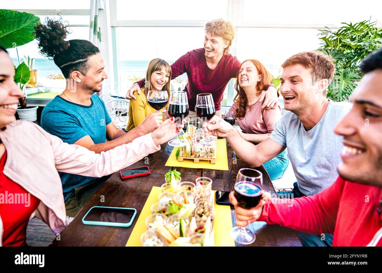 Gente felice milleniale che si diverte insieme bevendo vino in terrazza In casa privata festa - giovani amici mangiare finger food alla riapertura del ristorante Foto Stock