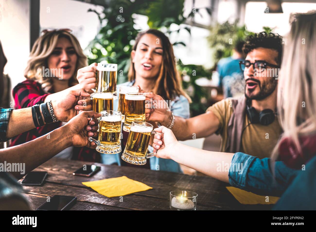 Amici che tostano birra al bar della birreria al coperto al roof party - concetto di amicizia con i giovani che si divertono a bere insieme all'happy hour Foto Stock