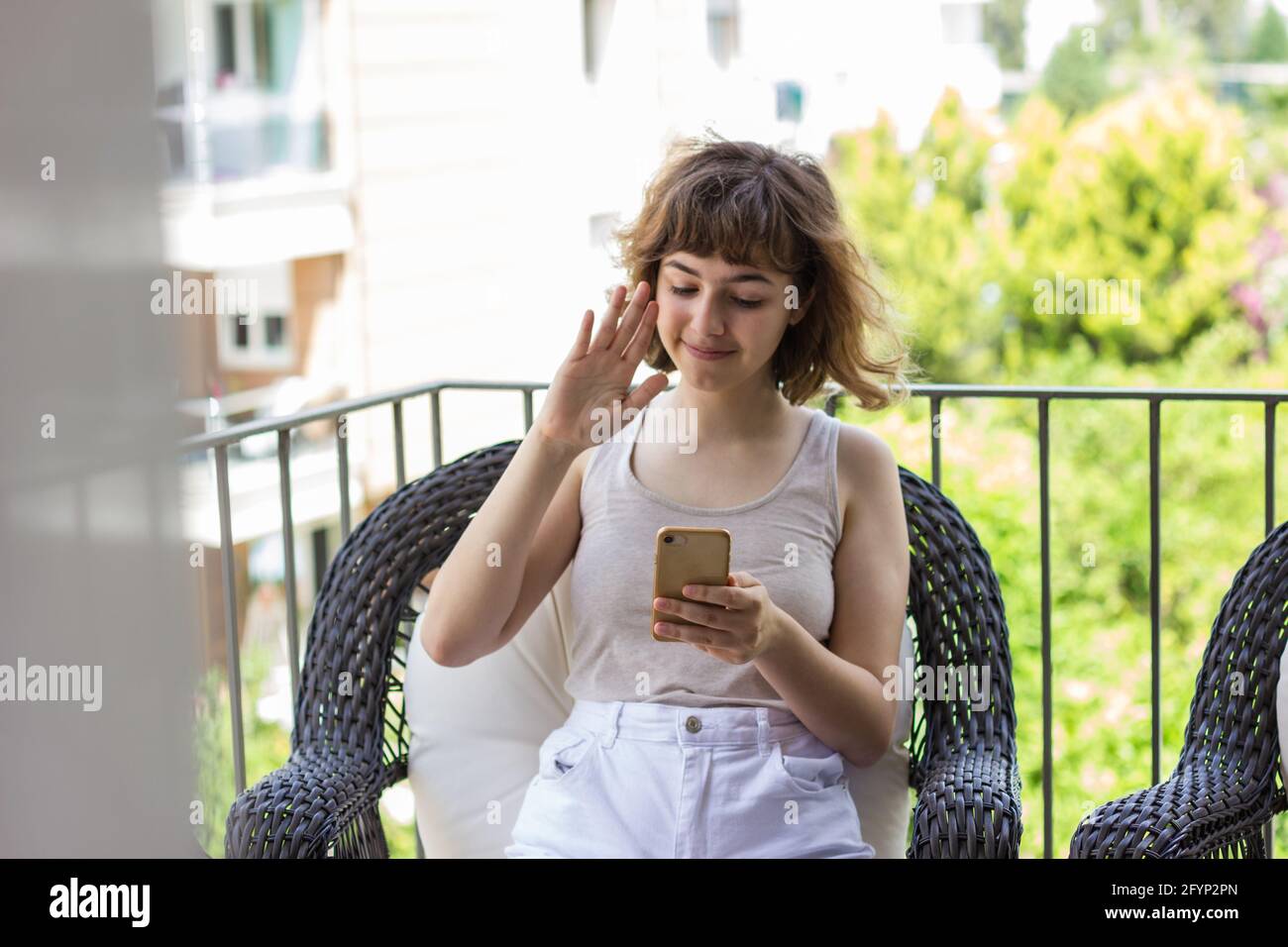 Bella ragazza giovane riccamente che parla per telefono sul balcone dell'appartamento Foto Stock