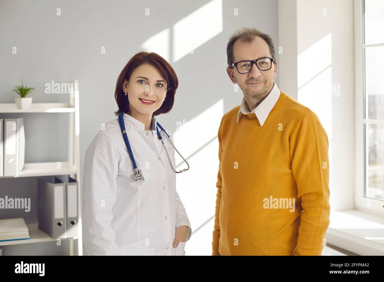 Ritratto di una dottoressa e di una paziente maschile senior in un luminoso ufficio di una moderna clinica privata. Foto Stock