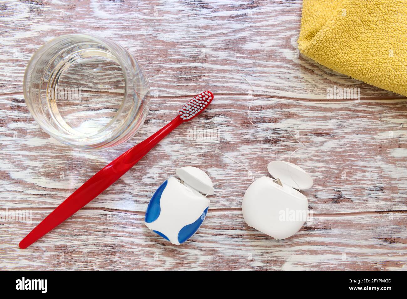 Filo interdentale, spazzolino da denti, bicchiere d'acqua e asciugamano, prodotti per la cura della persona, vista dall'alto Foto Stock