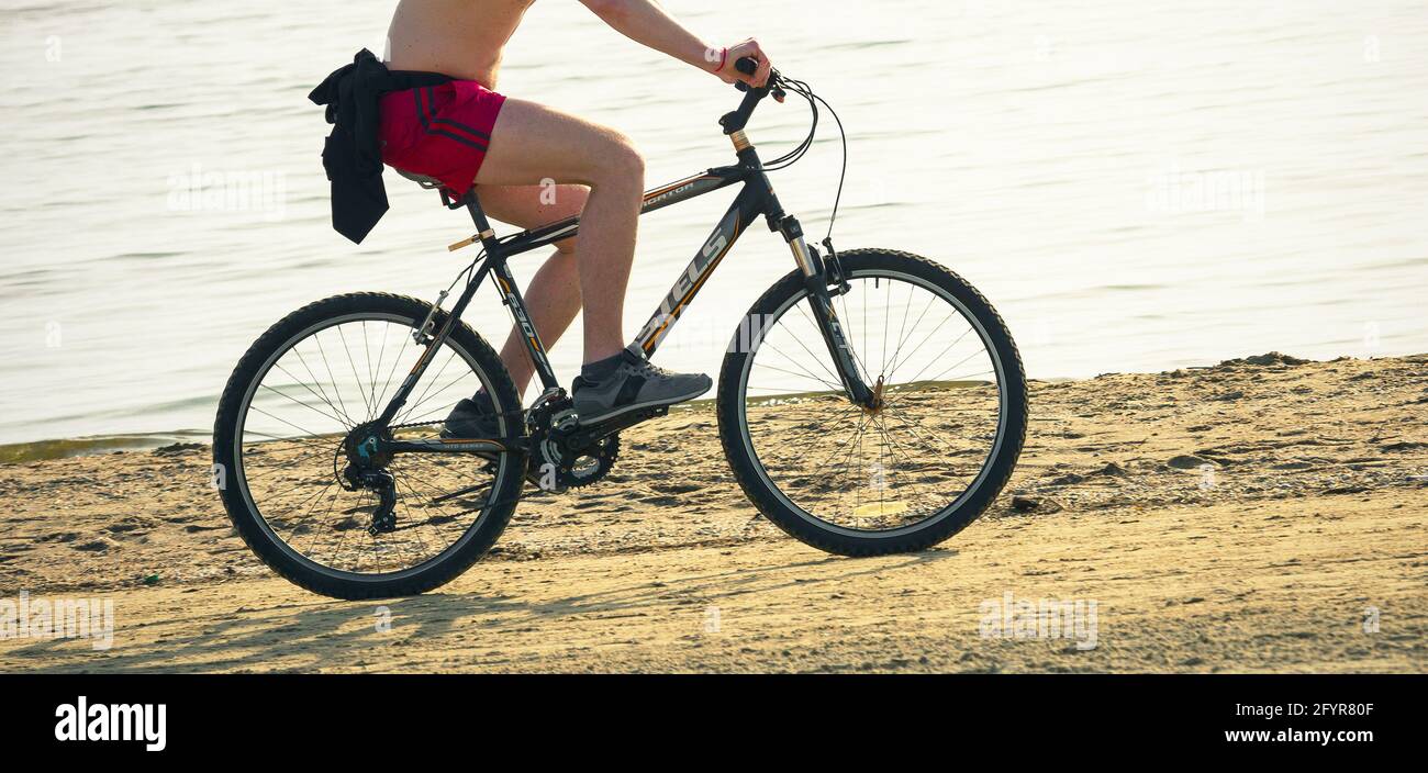 2019: Biker ride una bici russa Stels-630 in mountain bike lungo la soleggiata spiaggia di sabbia Foto Stock