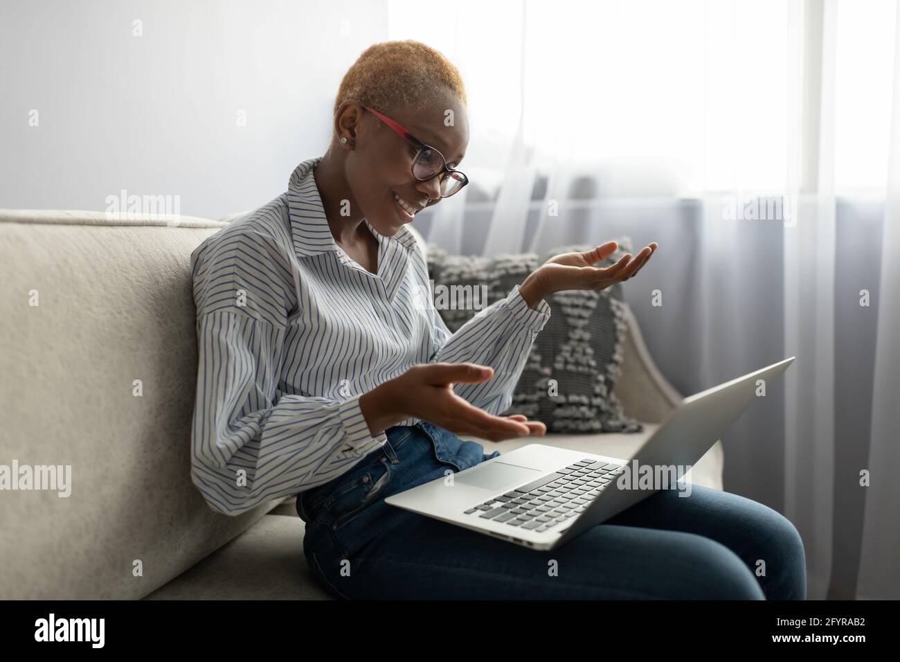 Donna nera sorridente che ha una riunione in linea via laptop a casa Foto Stock