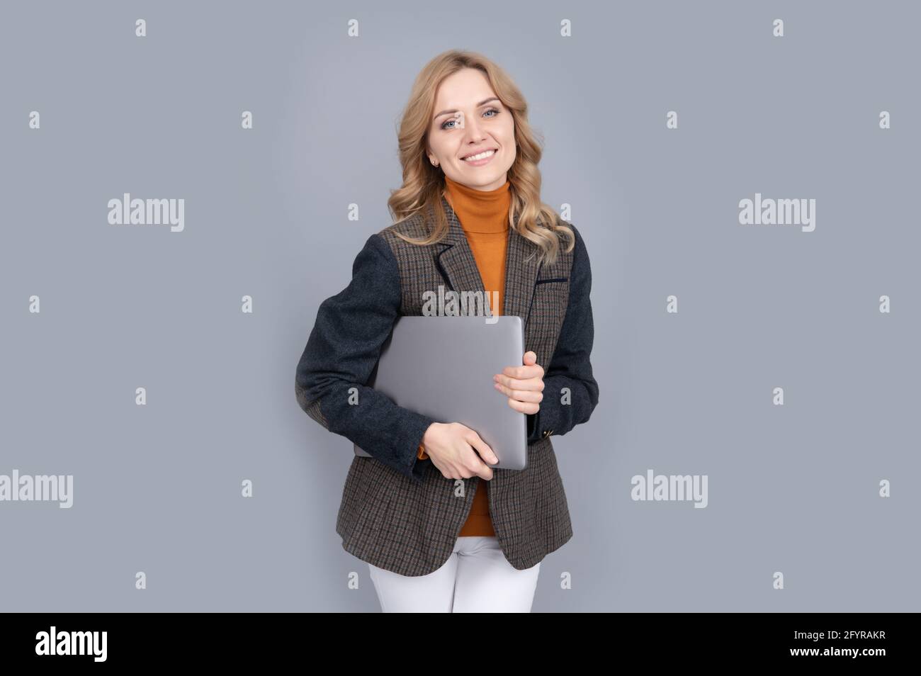 Donna felice in stile casual di moda tenere portatile computer portatile sfondo grigio, vita moderna Foto Stock