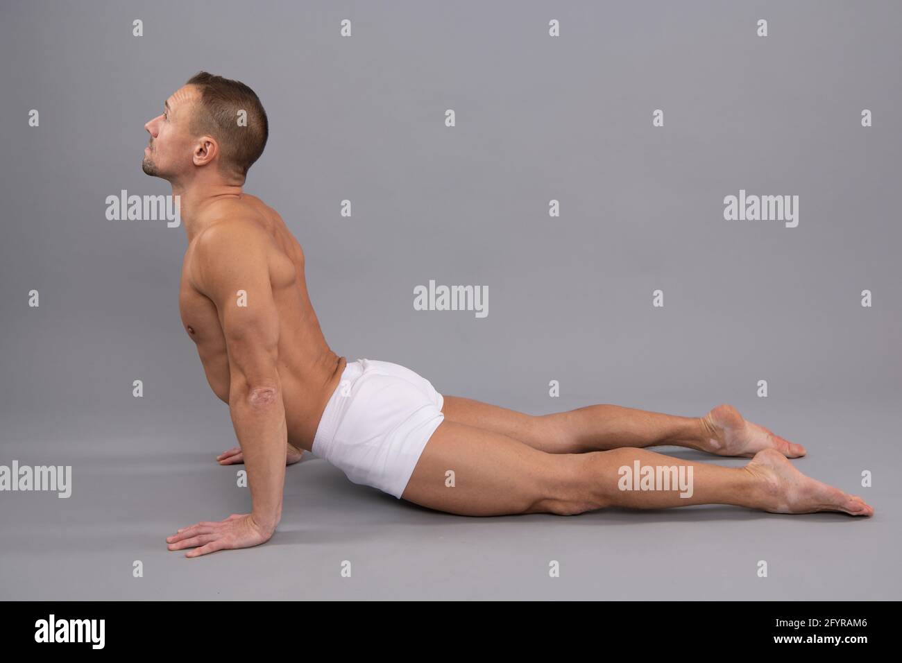 Yogi man do back-bending asana cobra yoga posa sfondo grigio, posizione del corpo Foto Stock