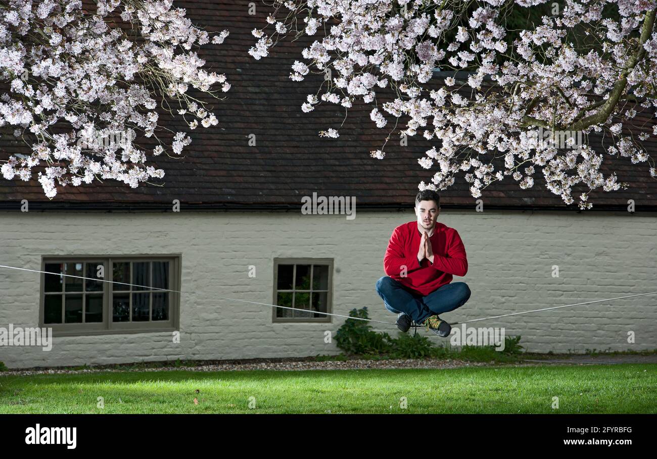 giovane uomo che pratica il suo equilibrio su una linea lenta tra due alberi Foto Stock giovane uomo che pratica il suo equilibrio su una linea lenta tra due alberi Foto Stock