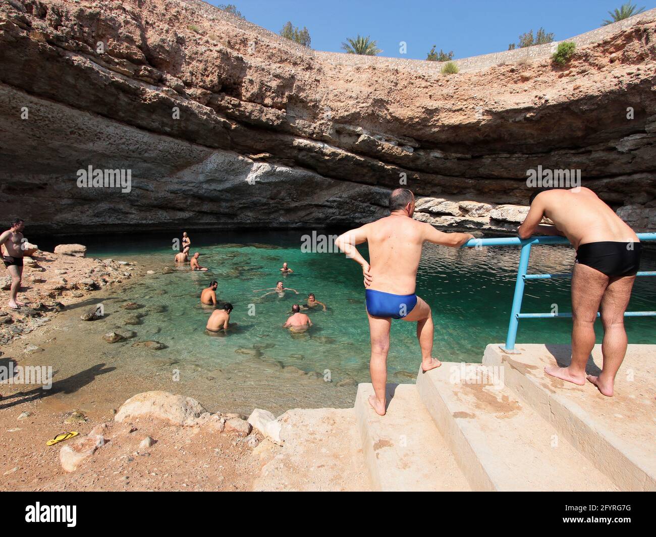 Uomini che indossano abiti da bagno bikini e altri bagnanti nella famosa  dolina di Bimmah in una giornata di sole. In Oman Foto stock - Alamy