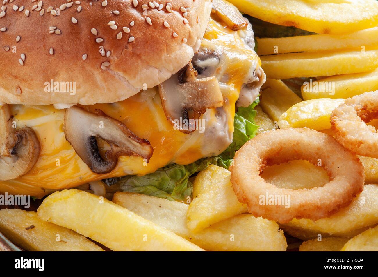 Delizioso cheeseburger con funghi e patate fritte Foto Stock