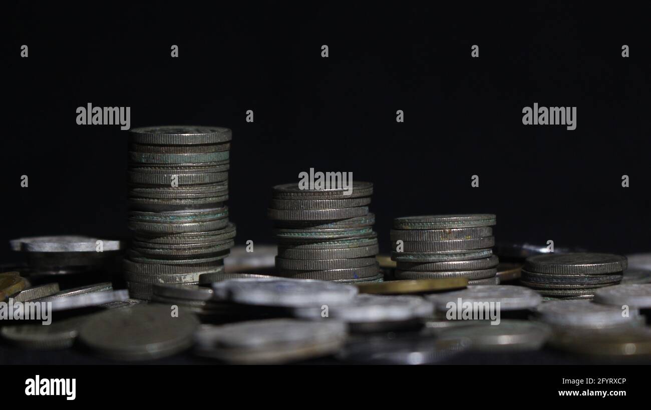 Primo piano di tre pile di vecchie monete d'argento con sfondo scuro Foto Stock