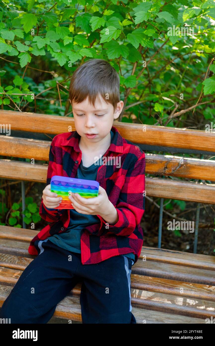 bambino di 8 anni che gioca con popit nel parco. bambino felice con  giocattolo. bambino che indossa abiti casual estivi luminosi. pop-up  multicolore. Antistress p Foto stock - Alamy