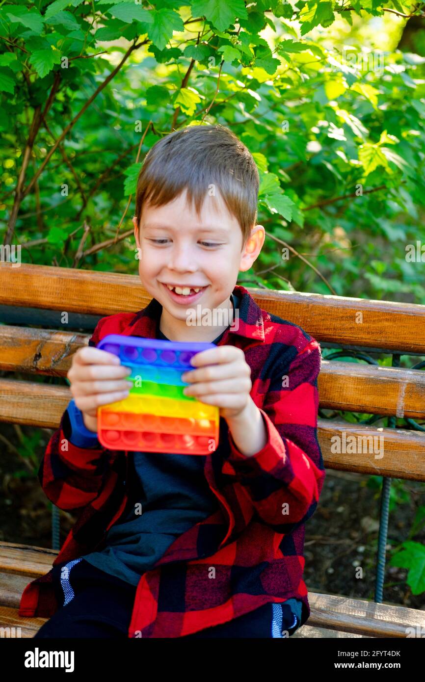 bambino di 8 anni che gioca con popit nel parco. bambino felice con  giocattolo. bambino che indossa abiti casual estivi luminosi. pop-up  multicolore Foto stock - Alamy