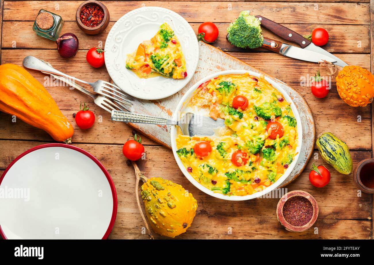 Casseruola vegetale con broccoli, pomodoro e zucca su vecchio tavolo di legno.Frittata Foto Stock