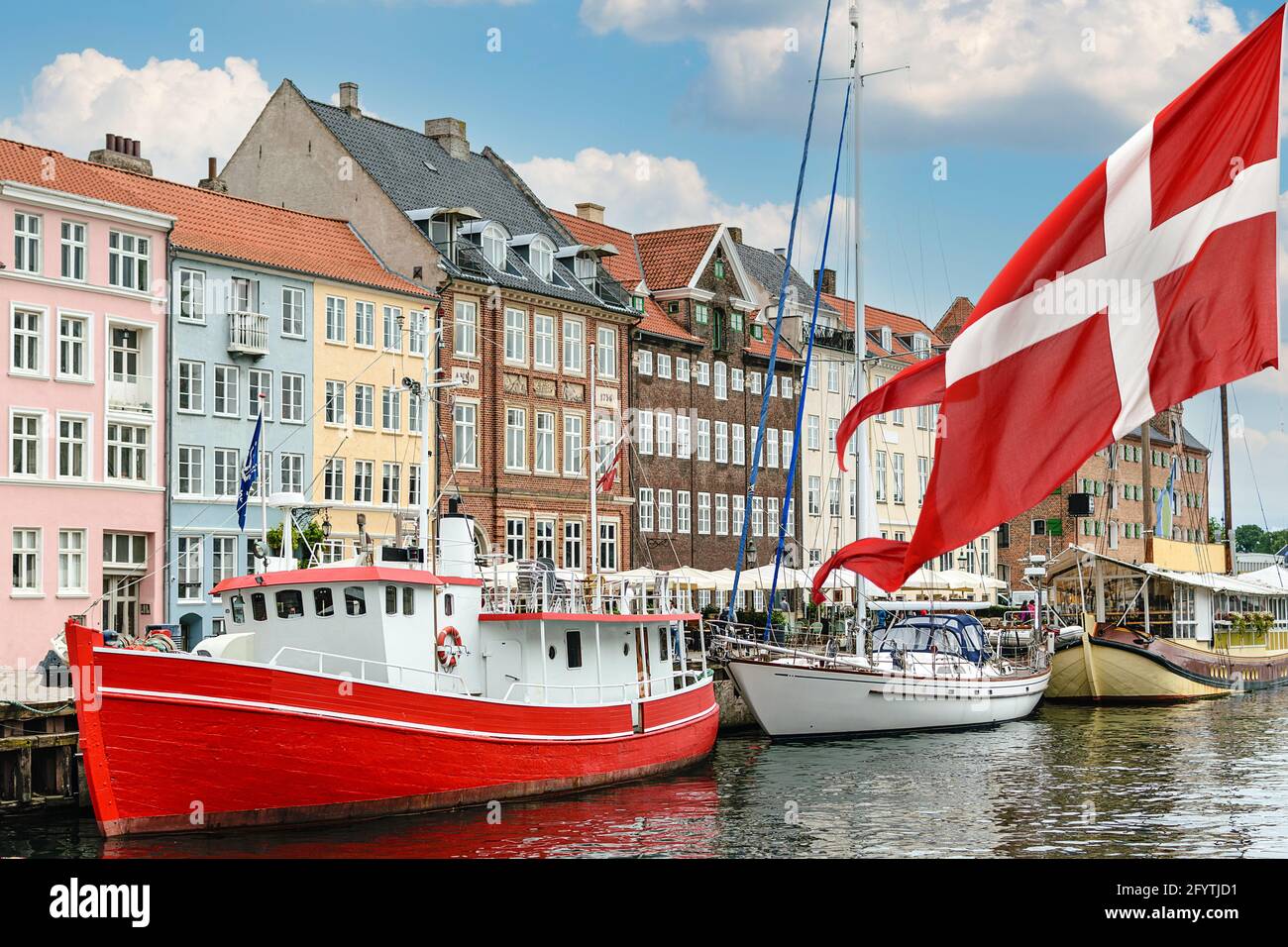 Nyhavn un porto del 17 ° secolo a Copenaghen con case e barche colorate tipiche con bandiera nazionale della Danimarca sul primo terreno. Foto Stock