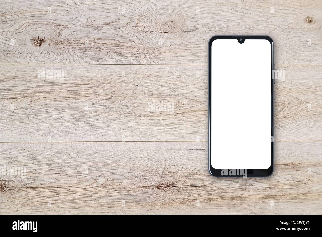 Vista dall'alto di un nuovo moderno mockup nero senza cornice per smartphone con schermo bianco vuoto su un tavolo di legno (spazio per la copia). Foto Stock