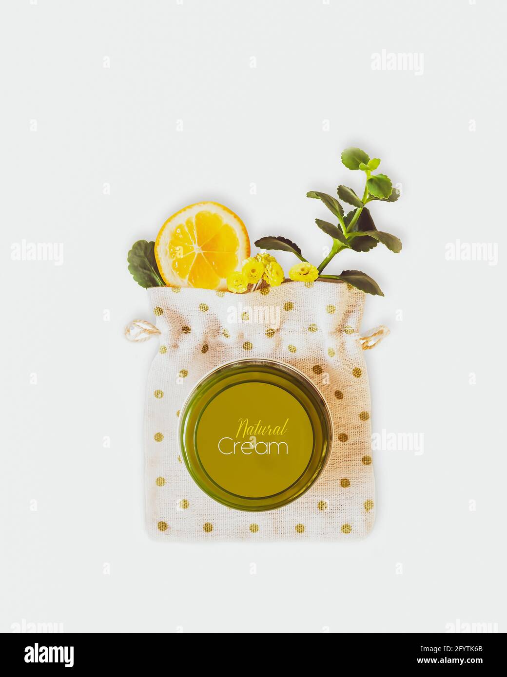 Composizione cosmetica verticale con un vasetto di crema con limone, fiori e un rametto verde su fondo bianco. Prodotti di bellezza a base vegetale Foto Stock