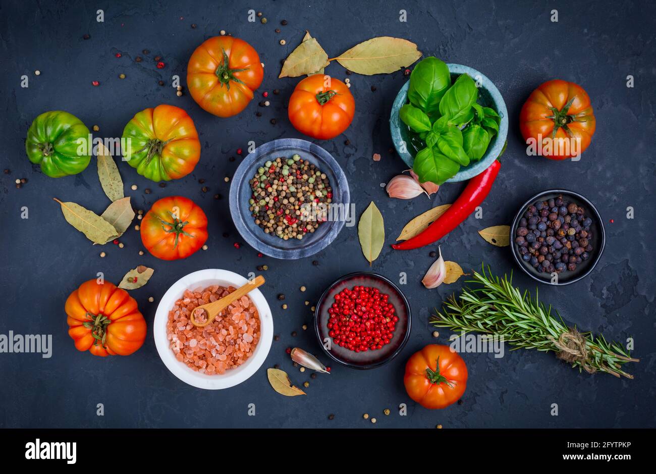 Assortimento di pomodori biologici, spezie ed erbe su fondo nero. Foto Stock