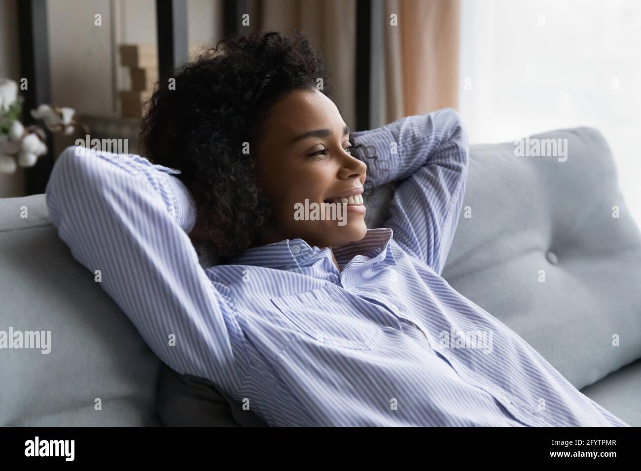 Sorridente afroamericana guarda a distanza sognando Foto Stock